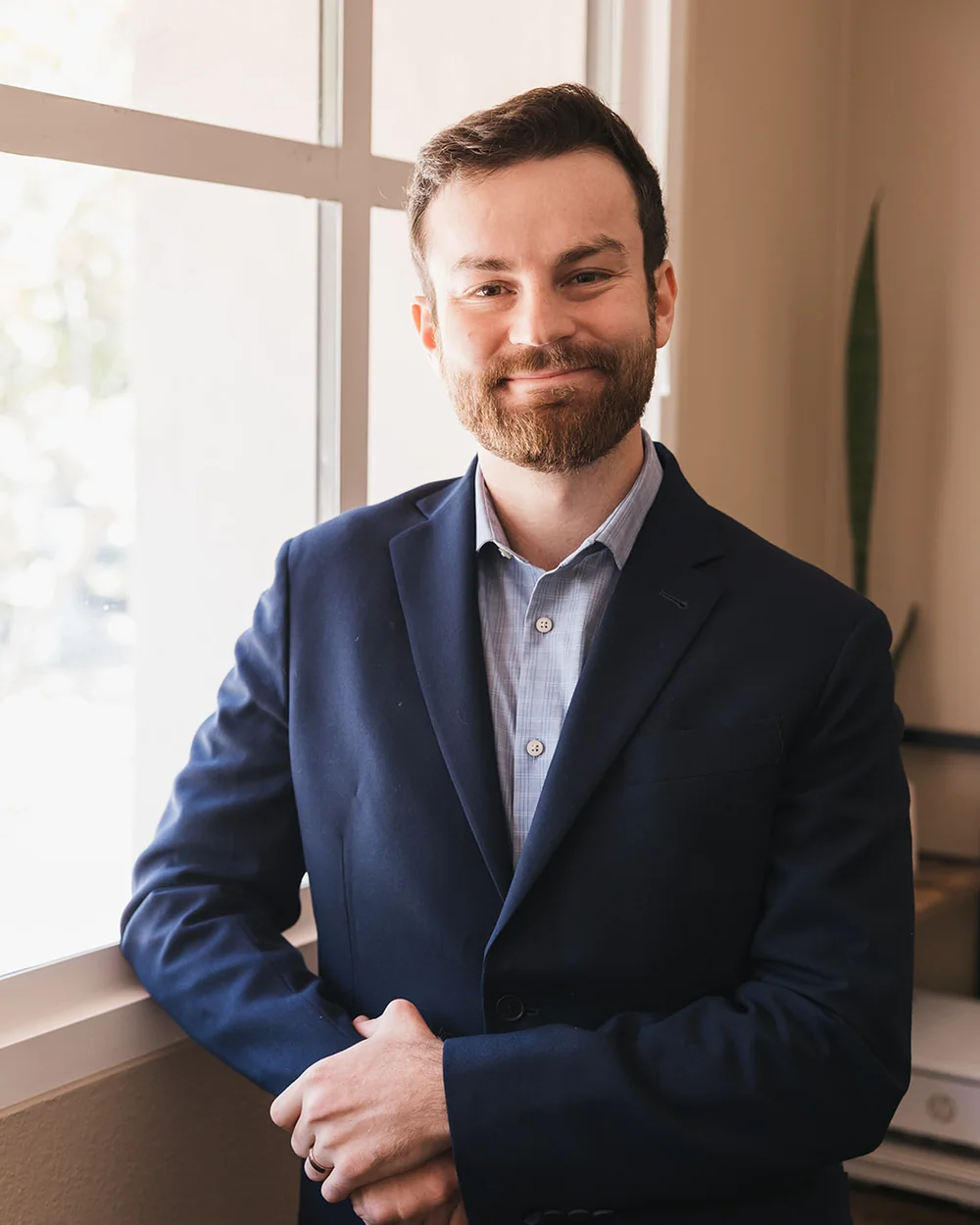 Nathan Rubinoff standing by an office window in a navy blazer
